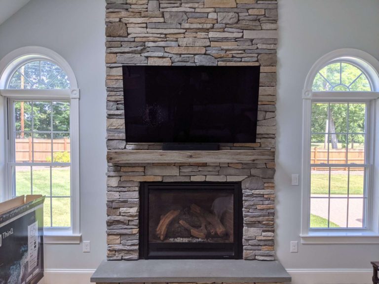 TV mounting on a stone surface above fireplace.